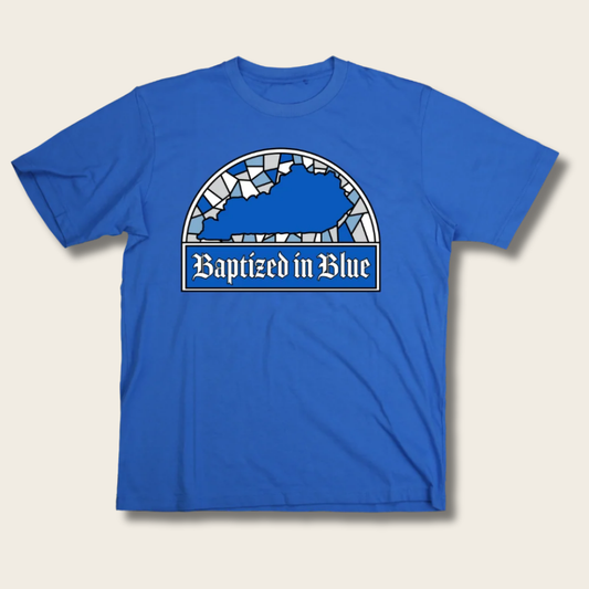 A royal blue short-sleeve t-shirt with a graphic on the chest depicting the state of Kentucky in a stained-glass style above the text 'Baptized in Blue' in a white banner.
