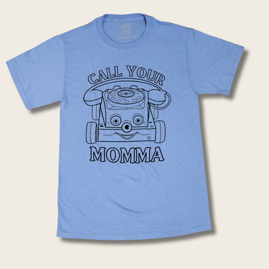 A light blue short-sleeve t-shirt with a black line art graphic of a retro rotary phone and the text 'CALL YOUR MOMMA' printed on the front, displayed against a light beige background.