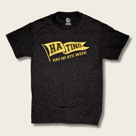 A black t-shirt with a yellow graphic on the front that reads 'HA TING HAS NO BYE WEEK' inside a banner design, displayed on a light beige background.
