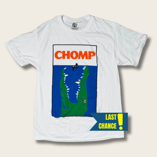 A white short-sleeve graphic t-shirt featuring a stylized alligator design with the word 'CHOMP' in orange above a blue and green alligator graphic. A yellow and blue 'LAST CHANCE!' banner is overlaid in the bottom right corner.