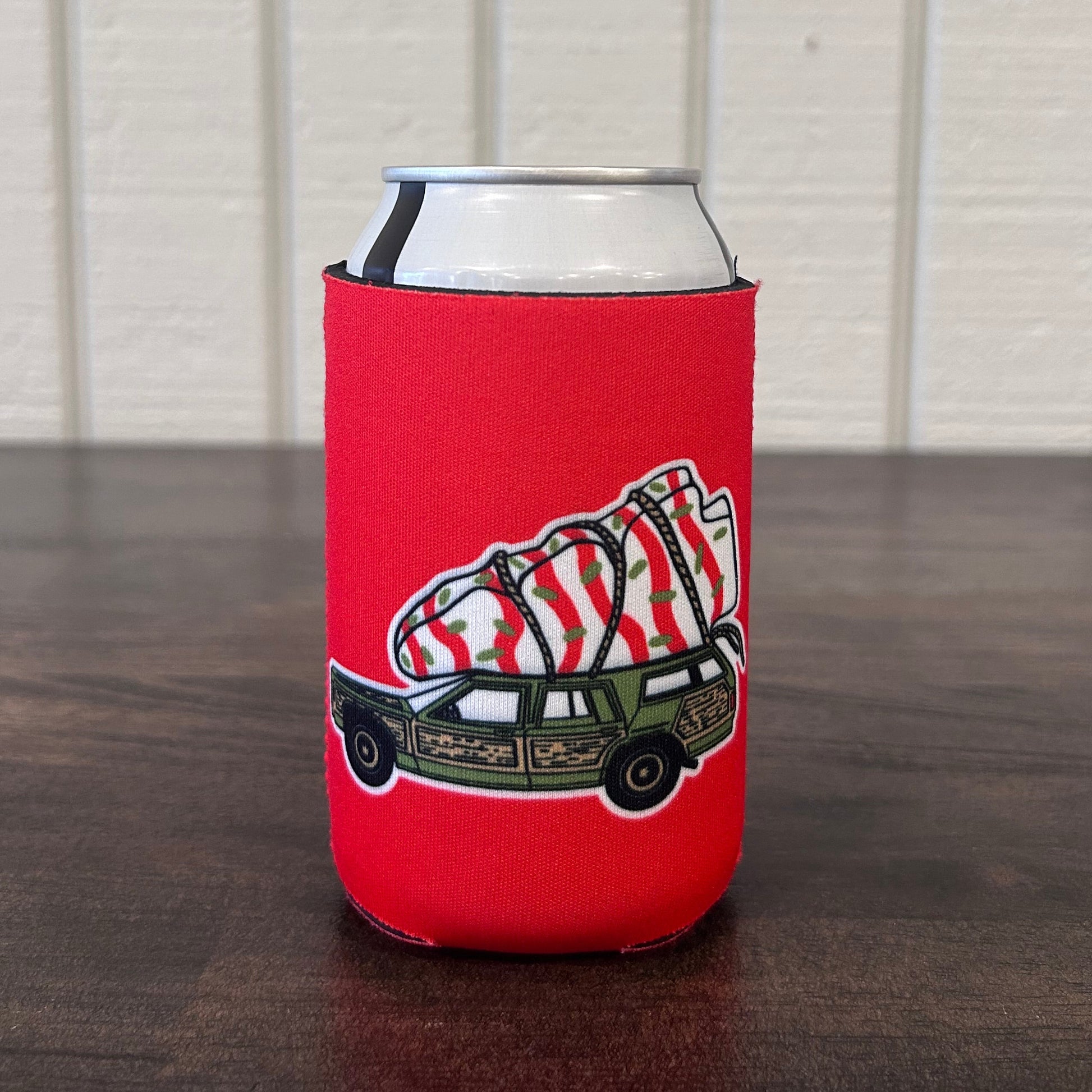 Red can cooler with a Christmas tree cake tied to the top of a car 