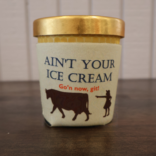 Humorous ice cream koozie with image of girl and cow and text saying "Ain't Your Ice Cream Go'n now, git!" on a wooden surface.