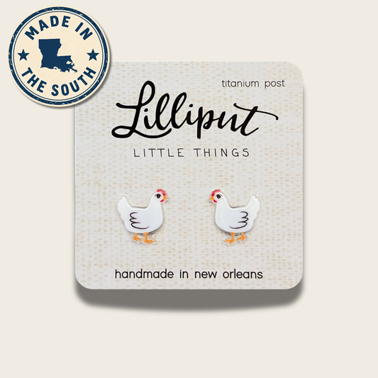 A pair of white chicken stud earrings on a textured cream display card. The card has the brand name 'Lilliput' and 'LITTLE THINGS' printed on it, along with ' titanium post' and 'handmade in new orleans'.