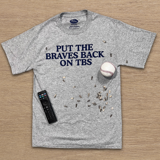 Funny Atlanta baseball shirt with bold text design on gray tshirt with baseball and remote on wood background